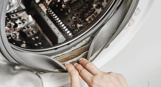 An unrecognizable woman cleans the washing machine